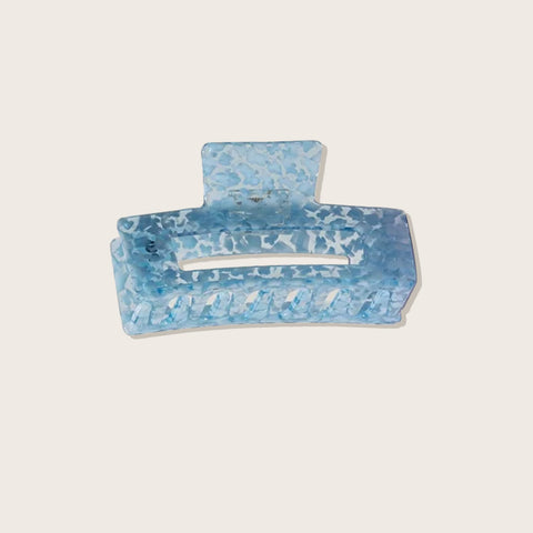 Pince à cheveux bleue Pixie Woo, outil de coiffure pour saisir et fixer les mèches, visible en gros plan sur fond neutre.