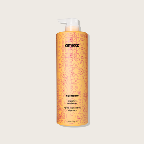 Revitalisant pour cheveux Amika Signature Normcore, flacon blanc avec pompe, soin capillaire nourrissant et revitalisant.