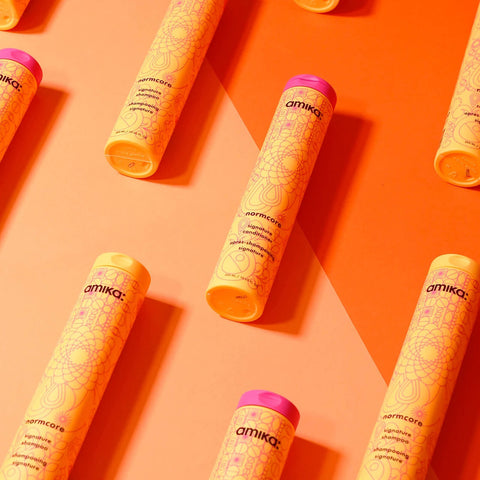 Revitalisant capillaire Amika Signature Normcore, bouteille élégante avec étiquette blanche et logo noir, pour cheveux sains et brillants.
