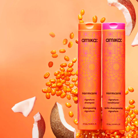 Revitalisant signature Amika pour cheveux, finition nourrissante et réparatrice, tube blanc avec logo noir.
