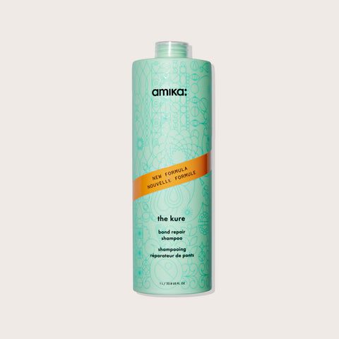 Revitalisant réparateur pour cheveux Amika The Kure, texture crémeuse et flacon élégant visible dans l'image.