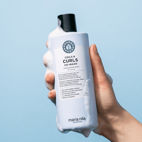 Shampooing boucles Maria Nila Coils & Curls Co-Wash pour cheveux bouclés, en bouteille blanche avec logo noir.