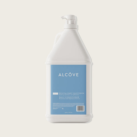 Cheveux avec revitalisant quotidien Alcôve, peignés et brillants, dans un flacon blanc avec étiquette.