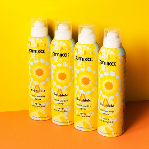Spray anti-humidité pour cheveux Amika The Shield, flacon spray noir avec étiquette blanche, protection contre l'humidité.