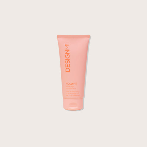 Crème coiffante DESIGN.ME HOLD.ME pour cheveux, contenant 90 ml, en tube blanc avec logo noir et texte.