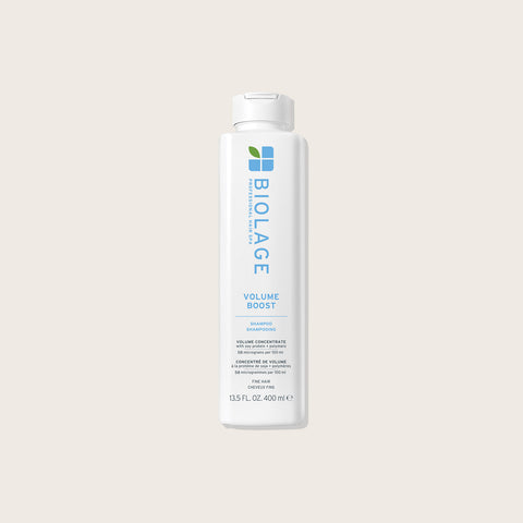 Shampooing volumisant Biolage Volume Boost pour cheveux, bouteille blanche avec logo et texture riche visible.