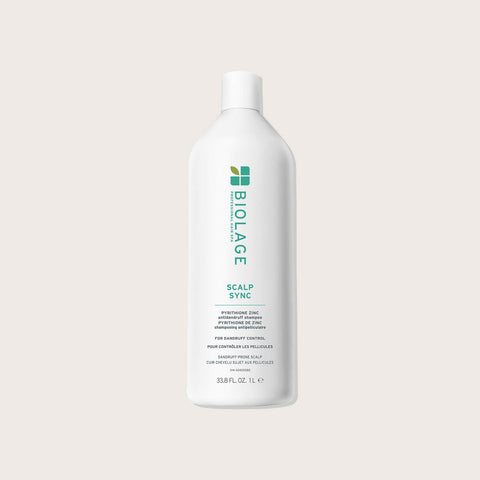 Shampooing anti-pelliculaire Biolage Scalp Sync pour cheveux, bouteille blanche avec étiquette bleue, en gros plan.