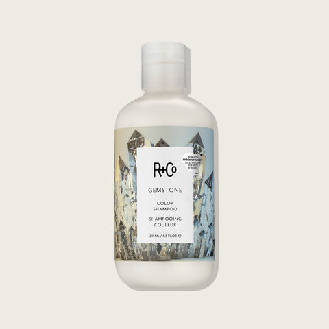 Shampooing couleur Gemstone de R+Co pour cheveux, bouteille élégante avec étiquette colorée et design moderne.
