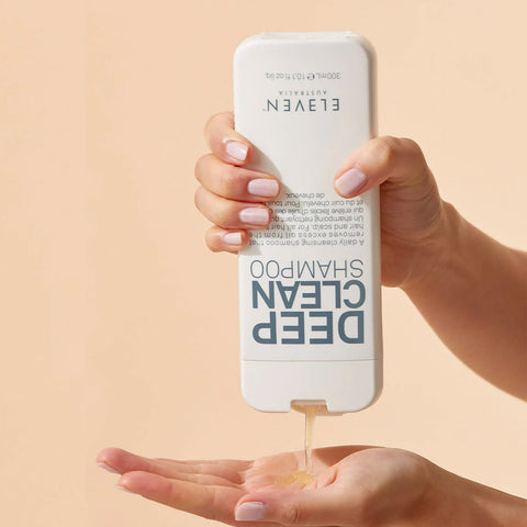 Shampooing quotidien Deep Clean de Eleven Australia pour cheveux, flacon blanc avec étiquette bleue, visible en gros plan.