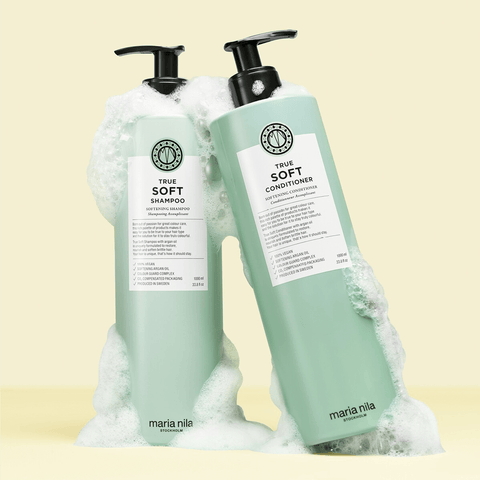 Shampooing assouplissant Maria Nila True Soft pour cheveux, bouteille blanche avec logo rose et détails en violet.