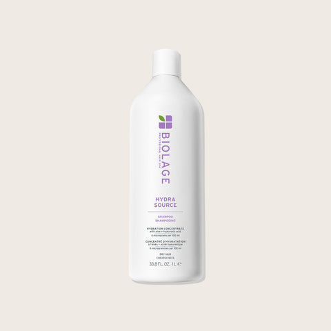 Shampooing hydratant Biolage Hydra Source pour cheveux, fluide et nourrissant, avec une bouteille élégante en arrière-plan.