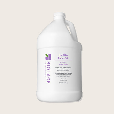 Shampooing hydratant Biolage Hydra Source pour cheveux, bouteille blanche avec logo bleu, texture crémeuse visible.